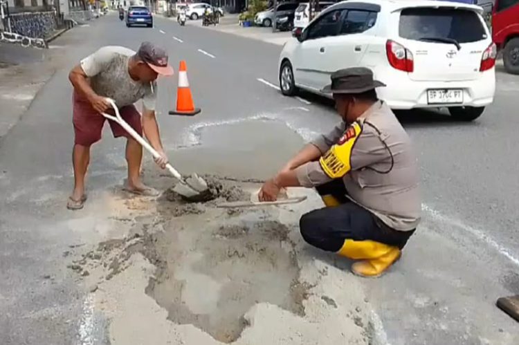 Salut, Warga dan Bhabinkamtibmas Gotong Royong Perbaiki Jalan Berlubang di Tanjungpinang